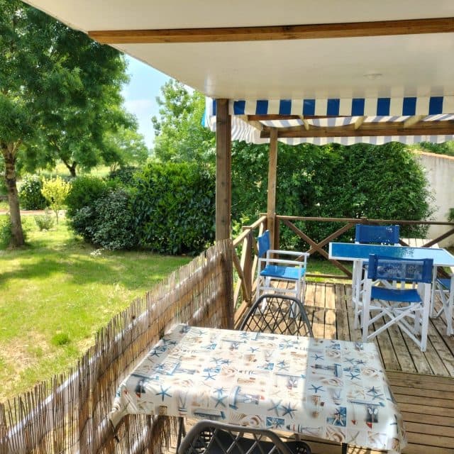 Terrasse ombragée sous auvent rayé bleu et blanc avec mobilier d'extérieur